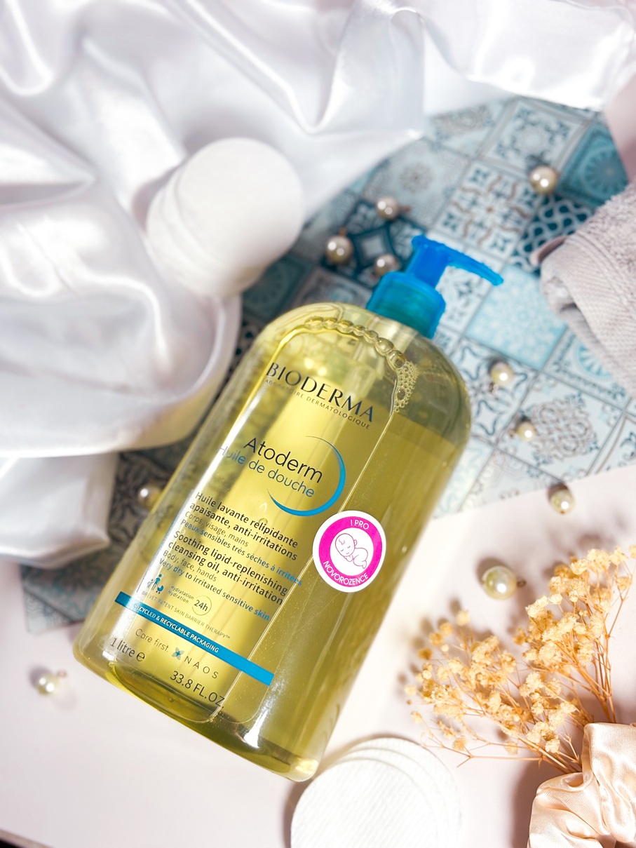 Le gel lavant Bioderma Atoderm Huile de Douche posé sur un fond soigné avec tissu satiné, perles, fleurs séchées, accessoire de bain et chouchou satiné.